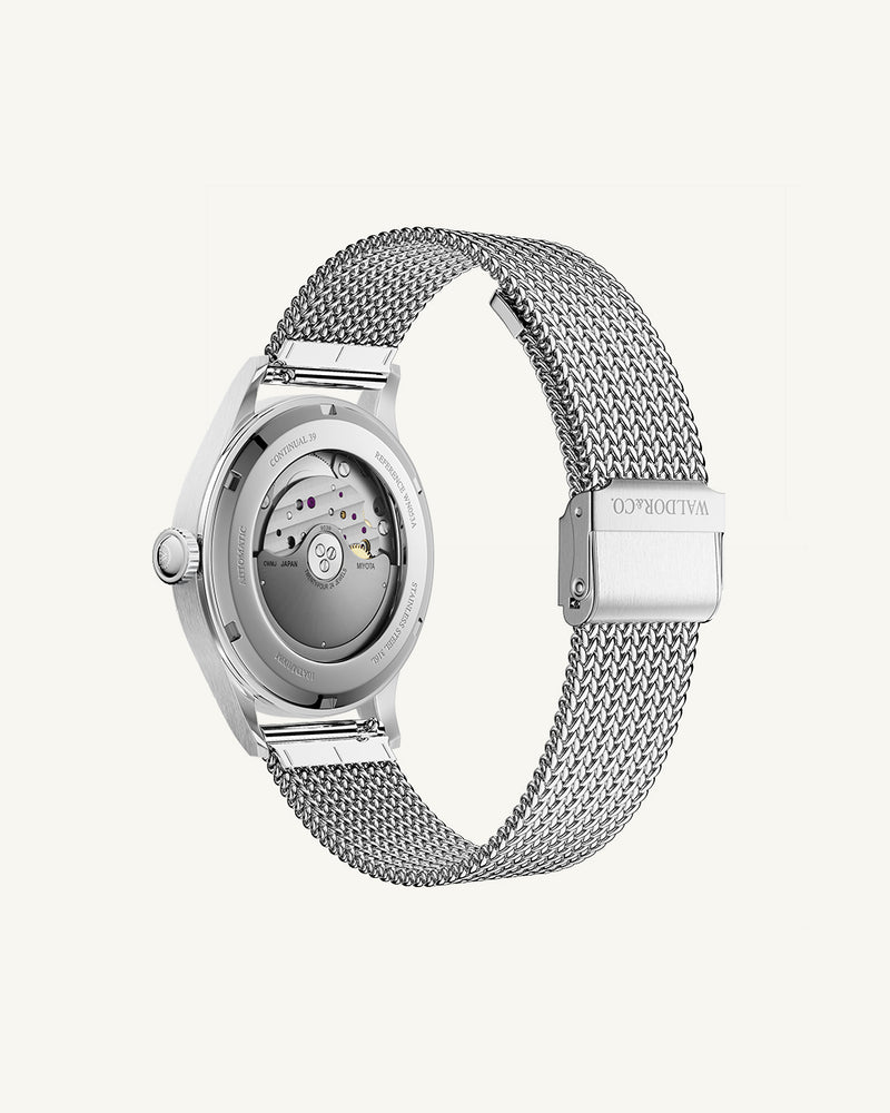 A round Automatic mens watch in Rhodiun plated 316L stainless from Waldor & Co. wit black double-layered dial in copper. Curved mineral glass with anti-reflective coating.Miyota 9093 movement. Mesh strap. The model is Continual 39 Amalfi.