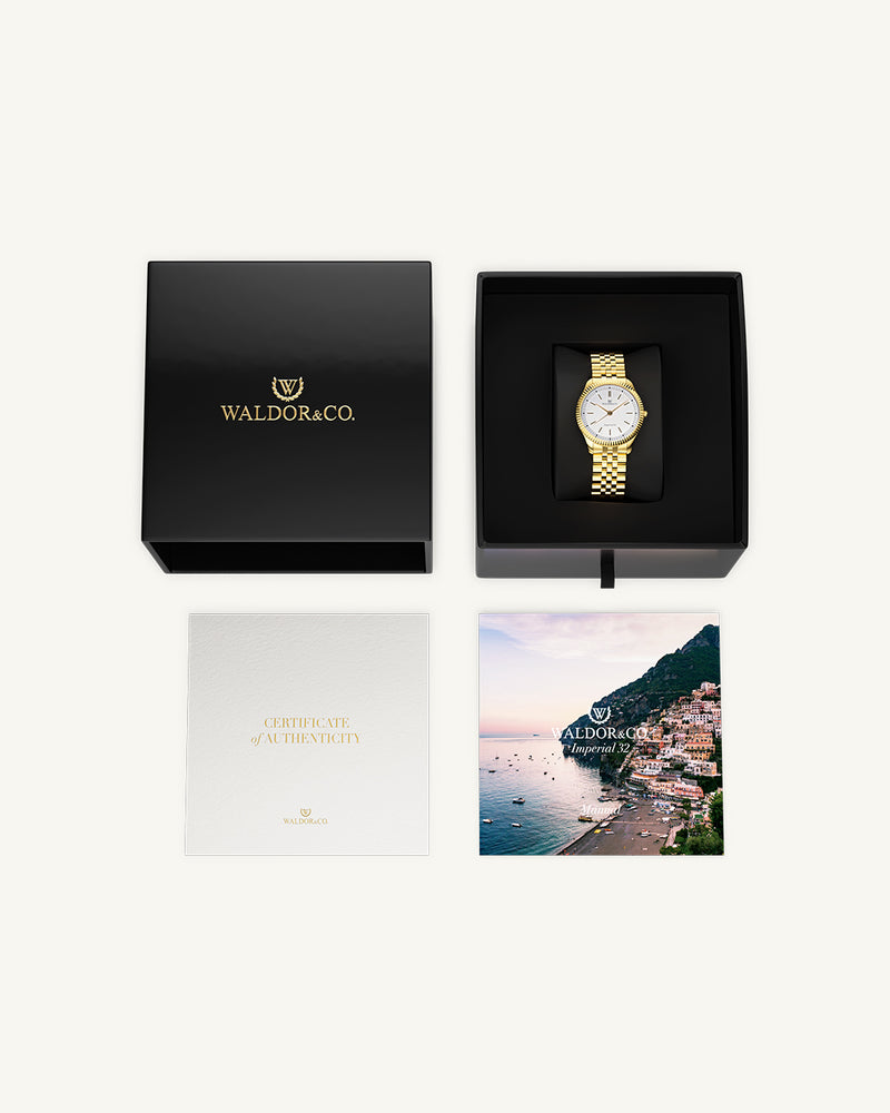 A round womens watch in 14k gold from Waldor & Co. with white sunray dial and a second hand. Seiko movement. The model is Imperial 32 Positano 32mm.