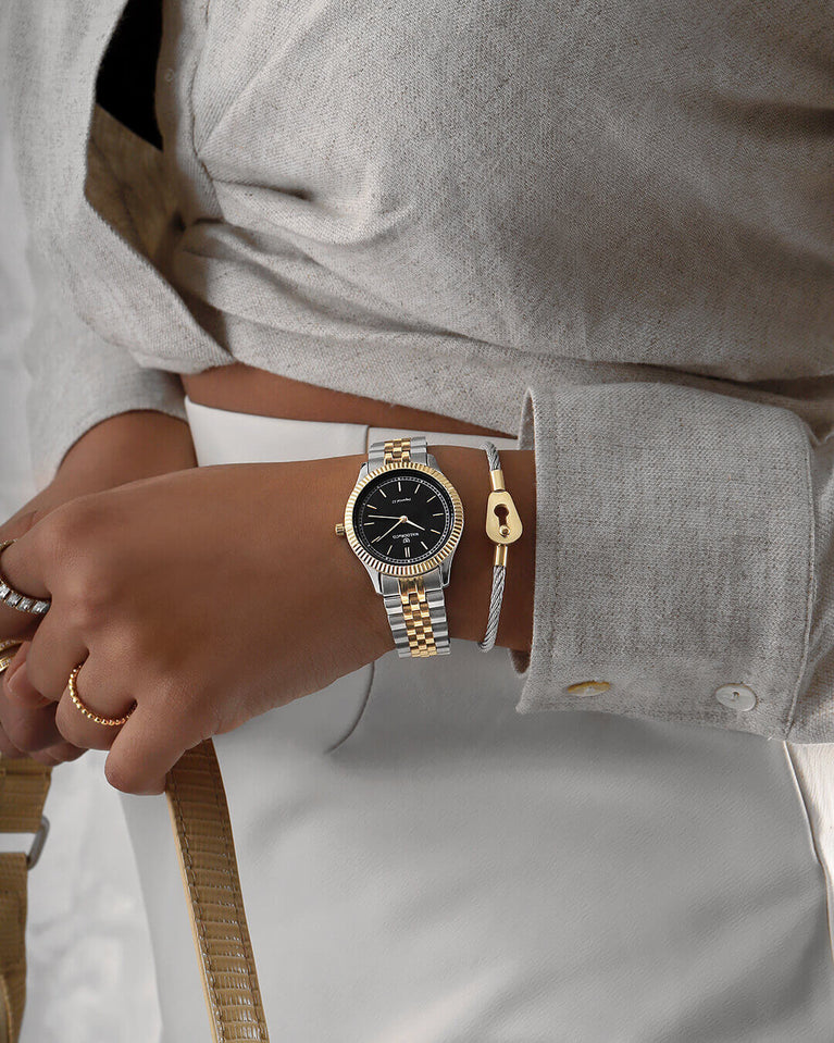 A round womens watch in silver and 14k gold from Waldor & Co. with black sunray dial and a second hand. Seiko movement. The model is Imperial 32 Positano 32mm.